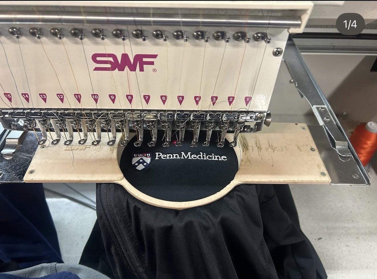 Penn Medicine logo being embroidered onto a black cap in a hooped embroidery machine