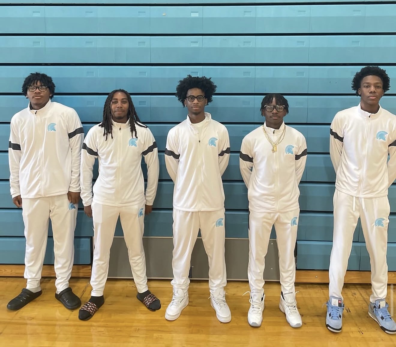 Five athletes in custom white embroidered team warmup jackets and pants